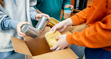 Close up of hands placing canned goods into cardboard boxes